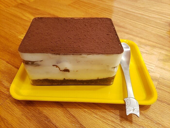 Tiramisu on a tray with a small spoon on a tray