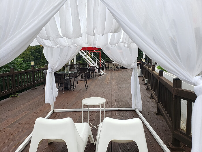 Two white chairs under a curtain tent
