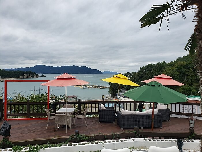 Umbrellas shading a sofa on a café balcony overlooking the sea and cliffs
