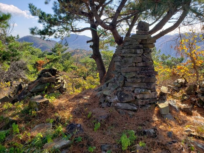 A beacon area with stacked rocks and other mountain peaks in the distance