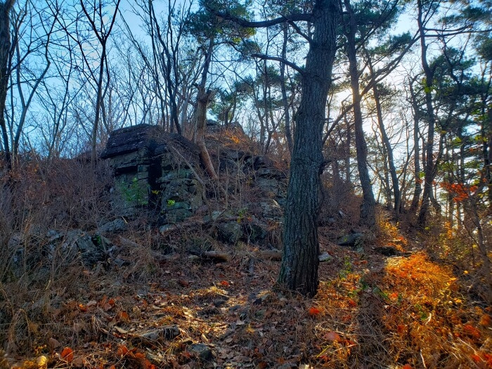 Sunshine shining onto the trail next to large rocks on the way to Suri Peak