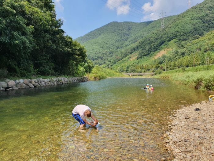 Nate and Baby Noah playing in a clean river by the mountains in Korea