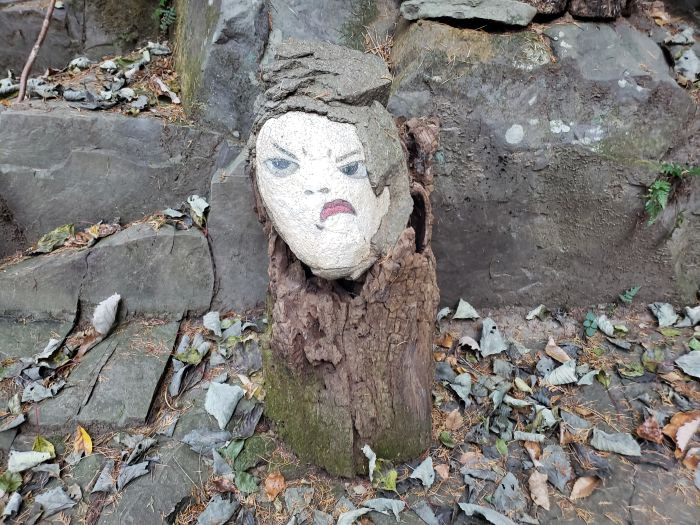 A painted frowning face on a rock resting on a stump