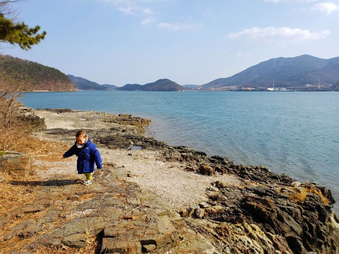 A toddler walking along a rocky shore in Korea