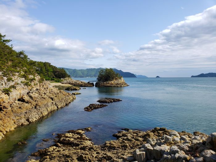 Blue water between rocks and an island during somewhat low tide