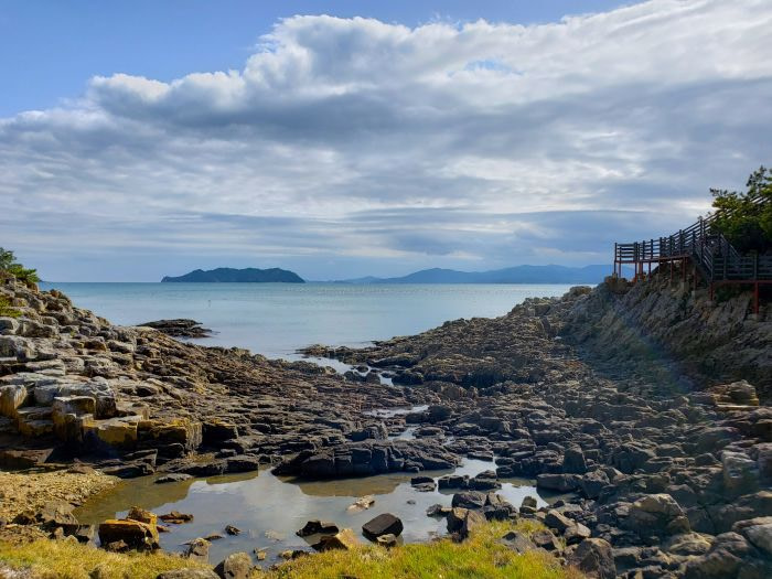 A rocky shore during low tide facing islands in the sea