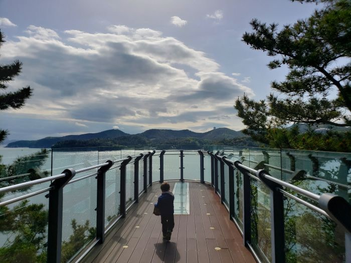 A toddler standing on an observation deck facing the sea