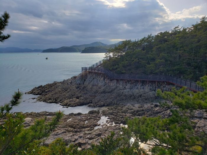 A winding boardwalk along a rocky Korean coast