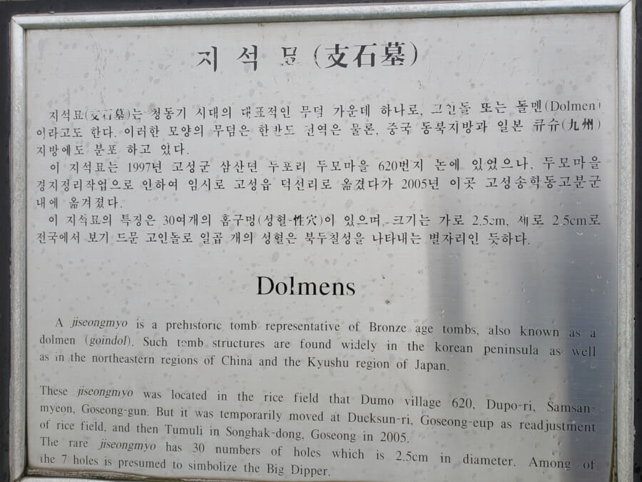 Closeup of signpost next to prehistoric rock tomb in both English and Korean