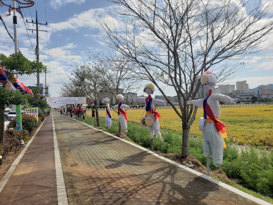 Handmade scarecrow-like figures lined up along the sidewalk for the festival