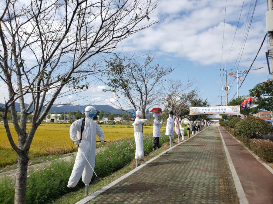 Handmade scarecrow-like figures lined up along the sidewalk for the festival