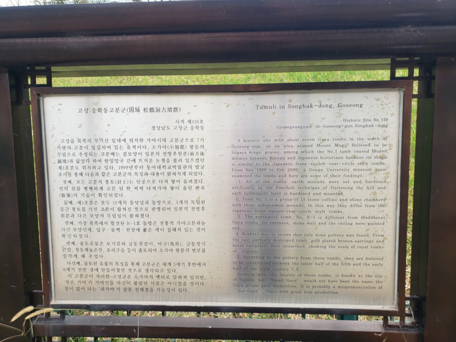 Closeup of signpost with wooden frame next to smaller tomb