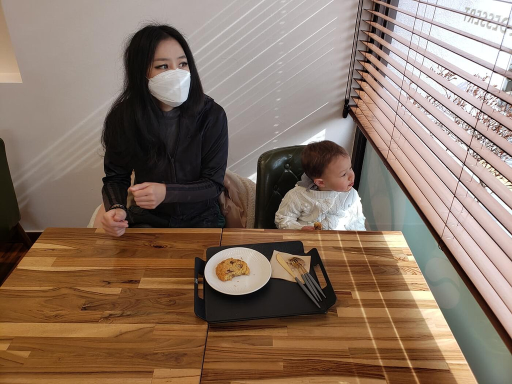 Baby and mom at a café table enjoying a chocolate chip cookie