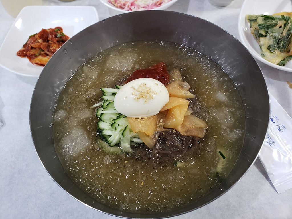 A bowl of icy mul naengmyeon with a boiled egg and vegetables
