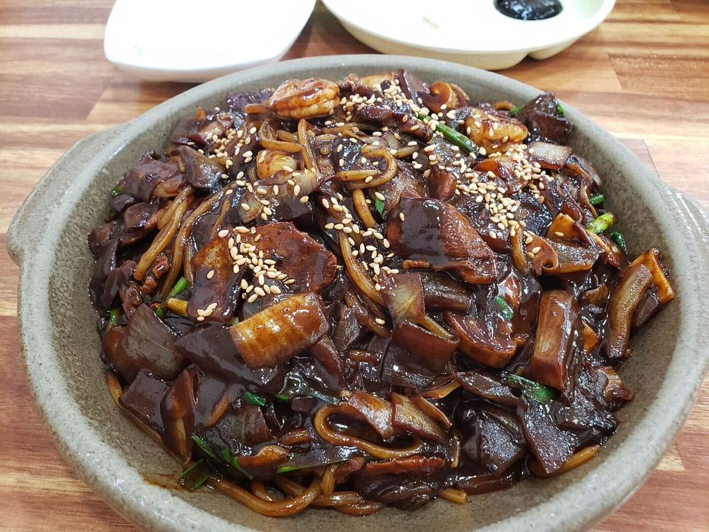 A bowl of Korean noodles in a dark sauce called jjajangmyeon