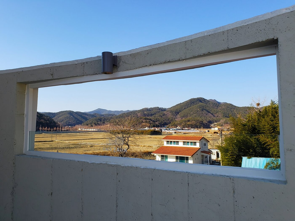 A concrete frame on a rooftop overlooking rice farms and mountains in Goseong, South Korea