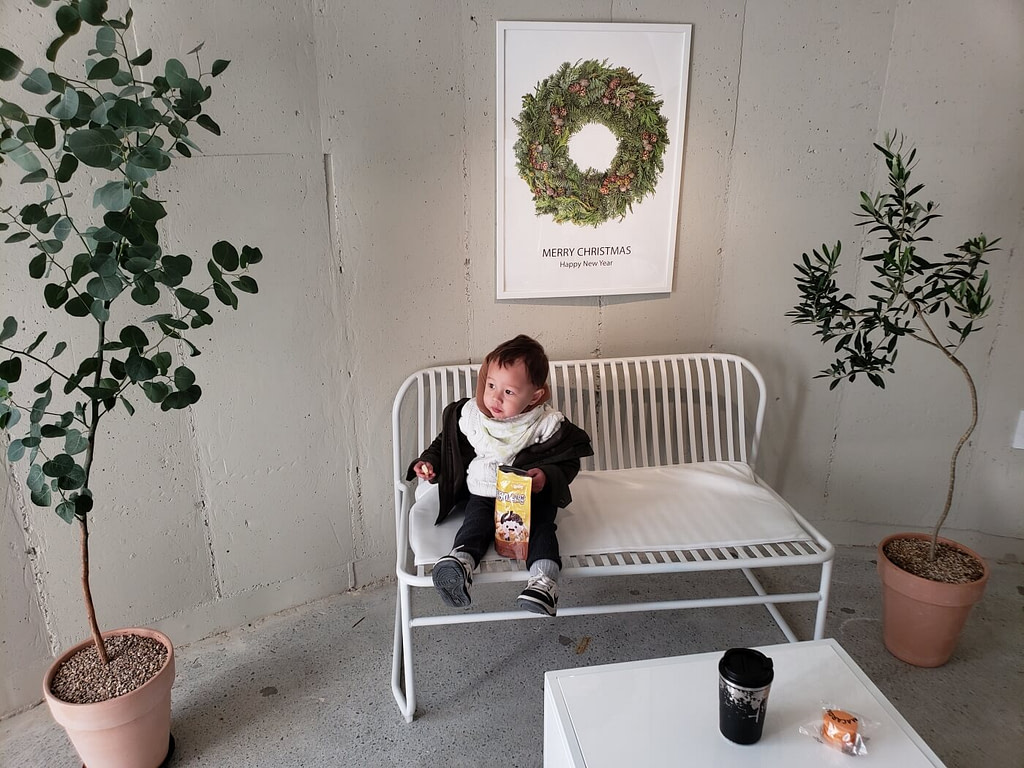 Noah sitting on a bench with a snack in a café
