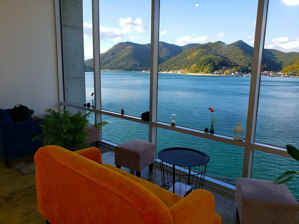 An orange couch by the window on the second floor of An Café in Goseong overlooking the sea and mountains