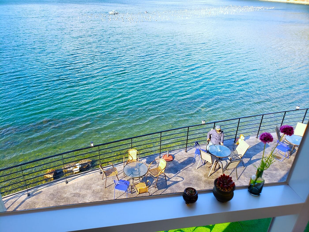 A person sitting at a table next to aqua water seen from above