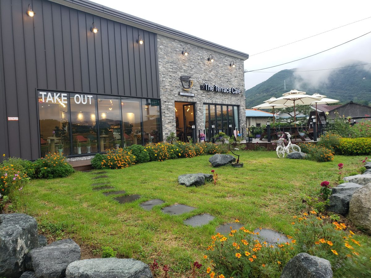A view of the outside of the The Terrace Café building with a grassy yard and flowers