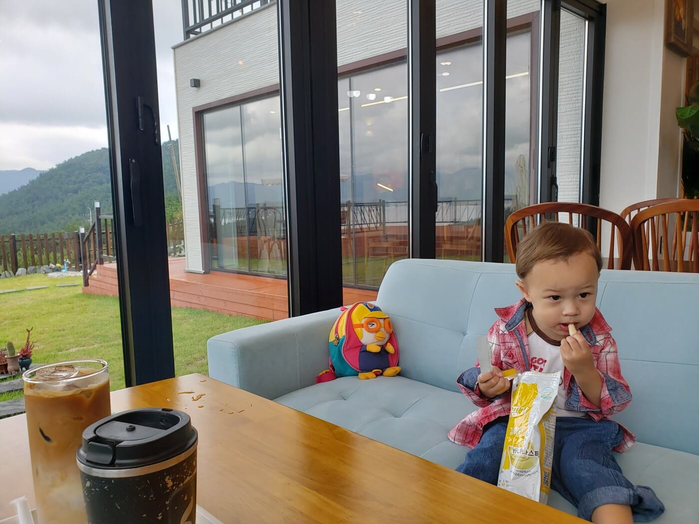Baby Noah on a sofa eating snacks next to the window