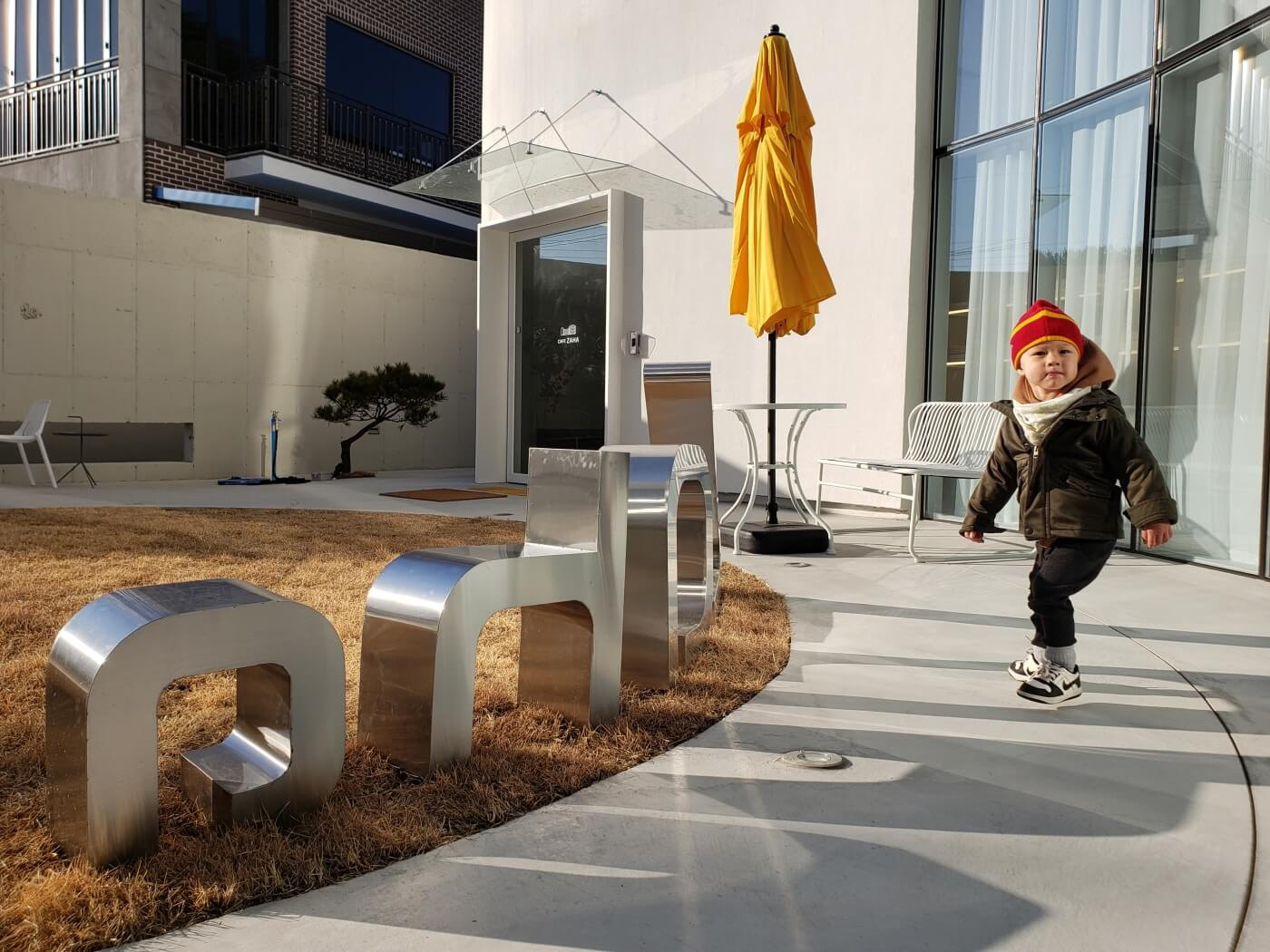 Baby Noah walking around a metal Zaha sign