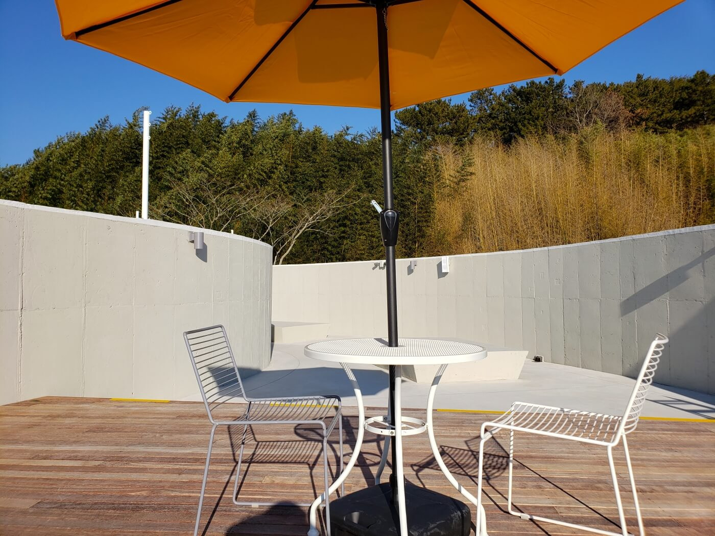 A pair of chairs and table underneath a yellow umbrella