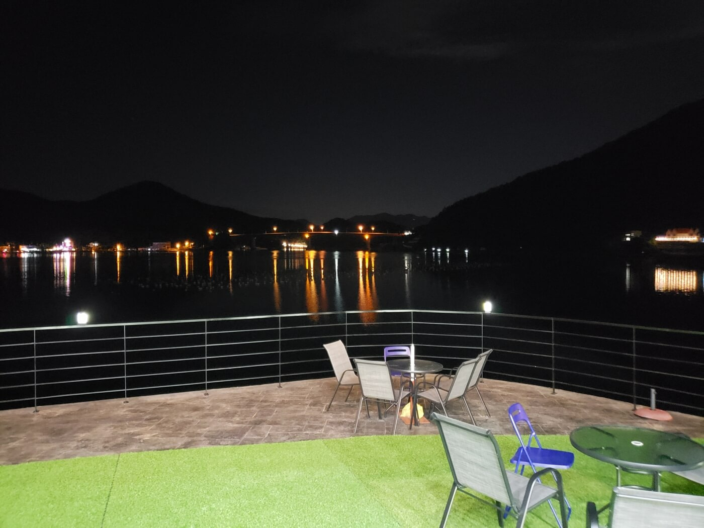 Tables and chairs next to water at night