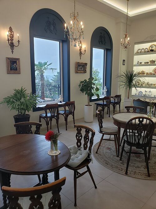 Candlesticks next to windows with a wall of dishes on shelves
