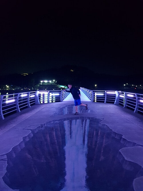 Nate on a trick art painting of a waterfall on Haejigae Bridge at night