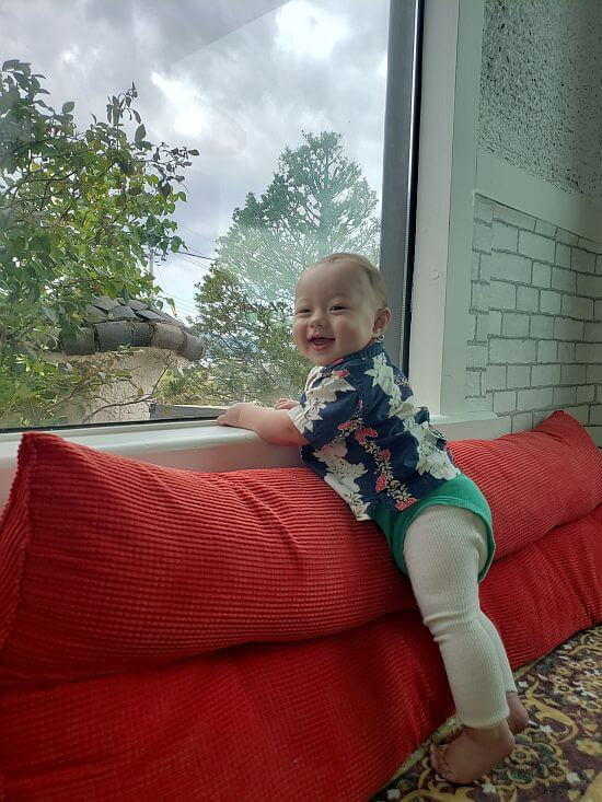 Noah standing against cushion by window