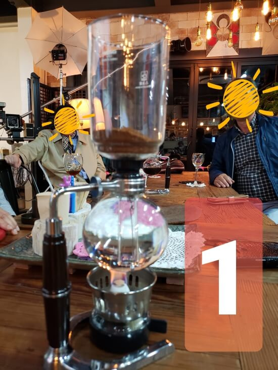 The first step of the process in preparing the siphon coffee by placing the coffee grounds and water inside the glasses and lighting the flame