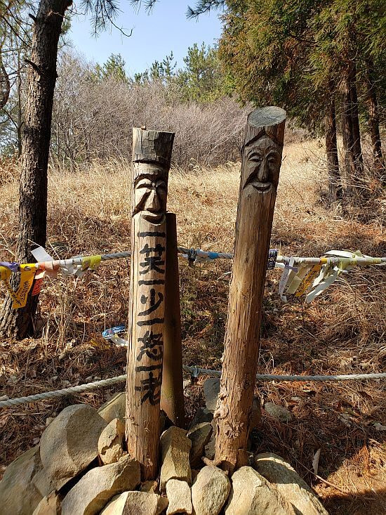 A pair of wooden sticks with carved faces and Chinese characters