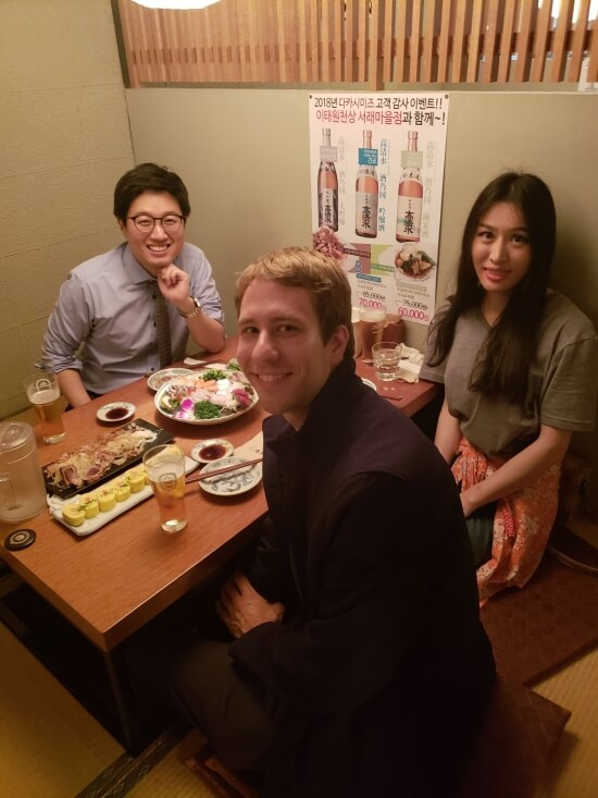 Nate and Alice sitting on the floor at a table with a friend in a Korean restaurant
