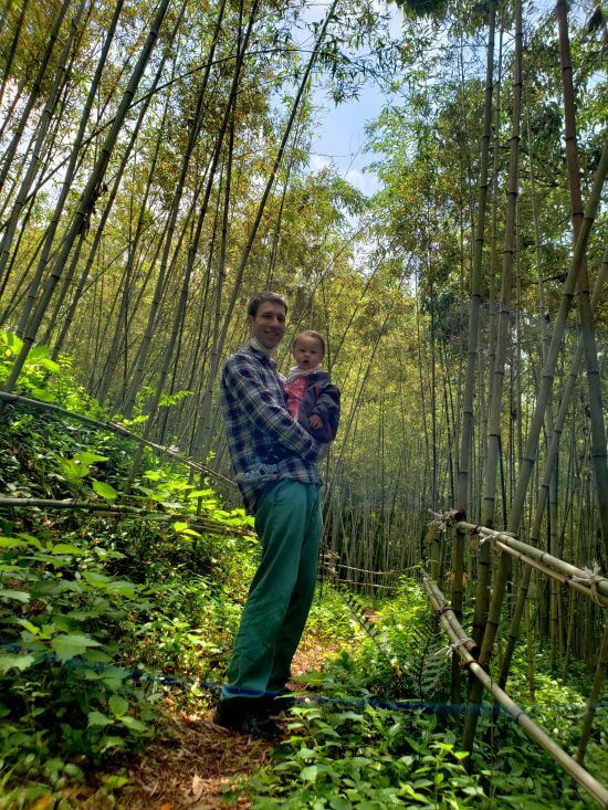 Nate holding baby Noah in a healing bamboo forest