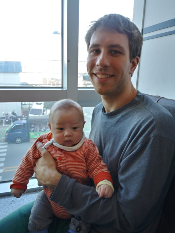 Nate holding Noah while sitting near the window at Taizen Café