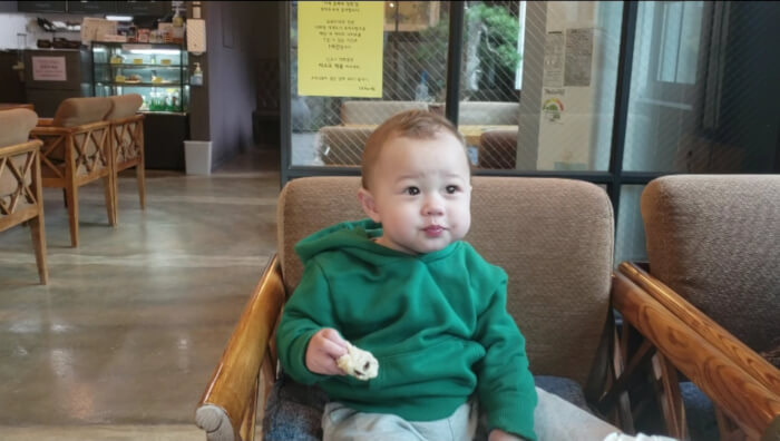 Noah eating in a café sitting in a char