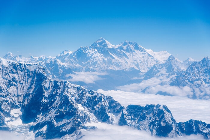 Mt. Everest among a range of snowy, rocky mountains in the clouds