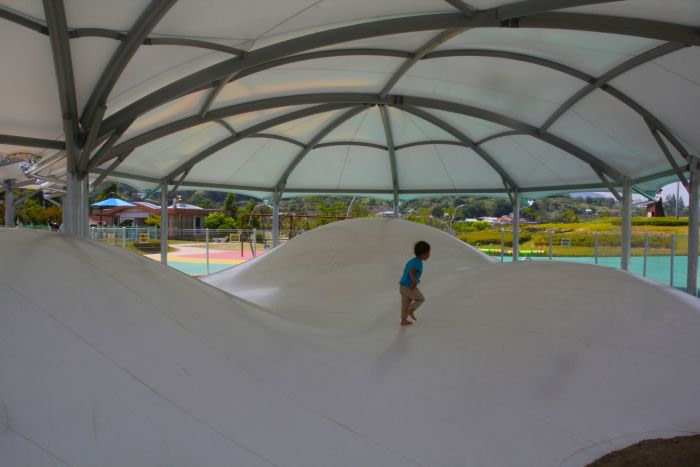 A toddler running in a bouncing pit with three mounds