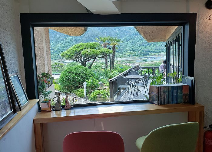 A view from two chairs against a window looking out over the patio across the village below