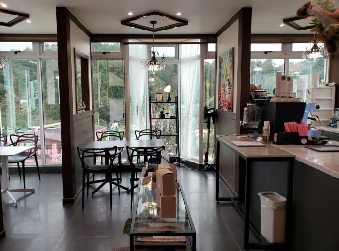 Tables and chairs next to windows and the Repos Café counter with cutouts in a wall separating tables