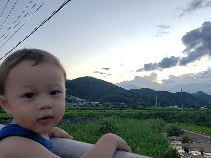 Noah looking at the camera hanging on a railing overlooking rural scenery