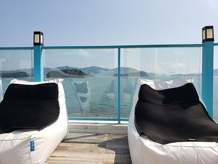 Two soft cushion chairs against a glass wall overlooking the sea and islands