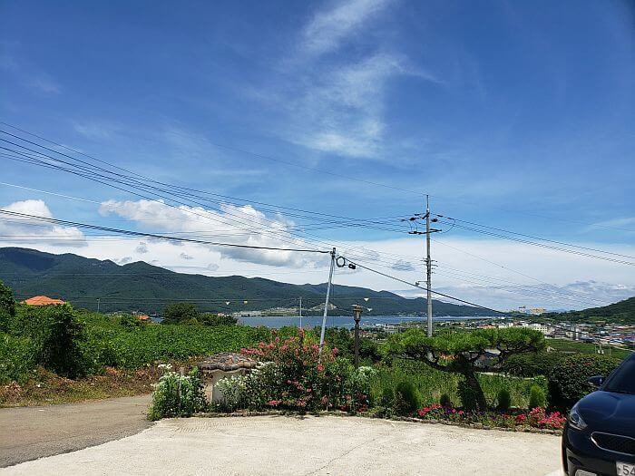 View of the mountains and sea from the parking lot bordered by flowering bushes
