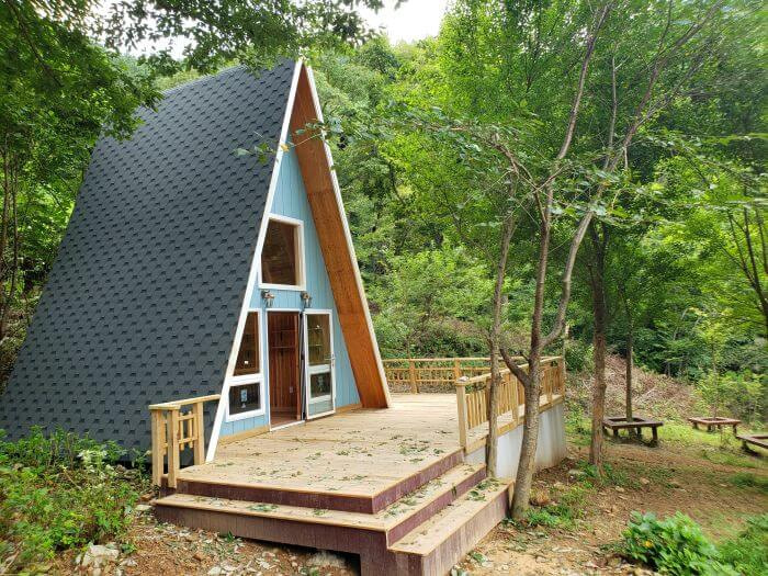 A triangular, small building with a deck in the forest
