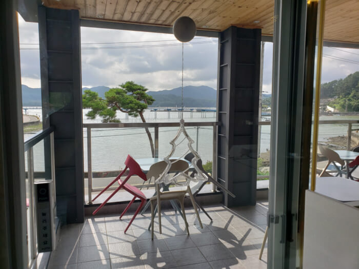 Sunny balcony with chairs against a table overlooking the sea and mountains