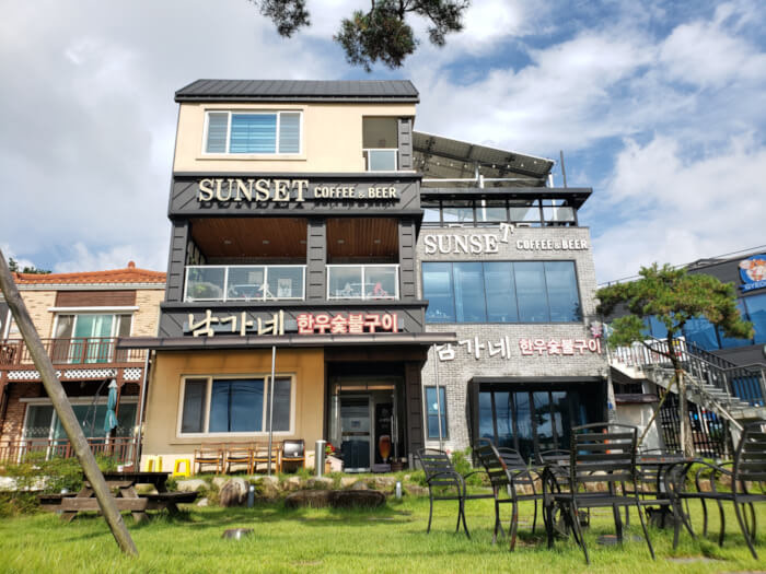 Exterior of café building with grassy yard in front with tables and chairs