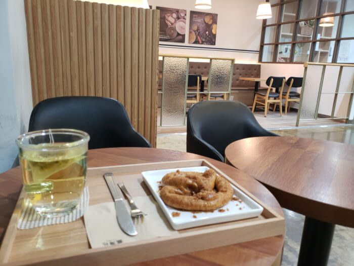 A pretzel covered in brown sugar on a tray with chamomile tea