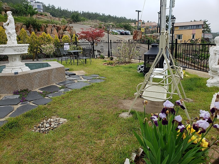 Flowers next to a swing in a courtyard with a water fountain in the middle