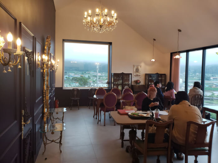 Tables on second floor with chandelier and large windows
